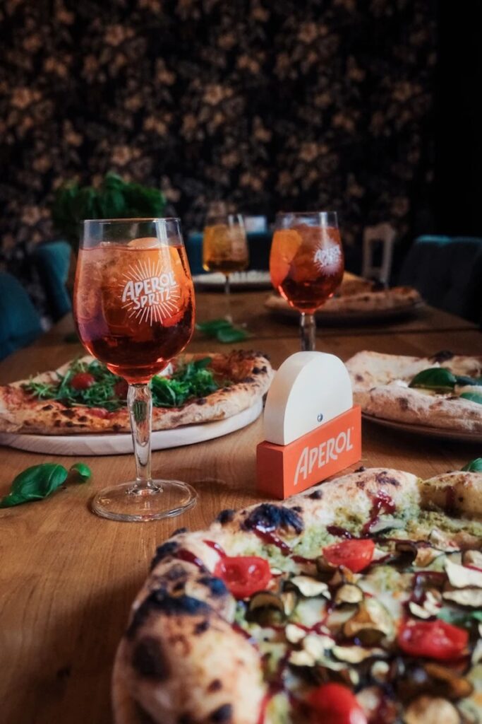 Pizza d’autore e cocktail leggeri: perché l’Aperol Spritz è l’abbinamento ideale per impasti ricercati, burrata, mortadella e salumi nobili.